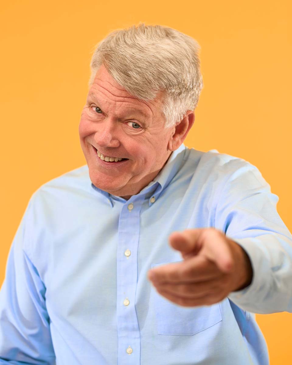 Senior man engaging yellow background NYC corporate headshot